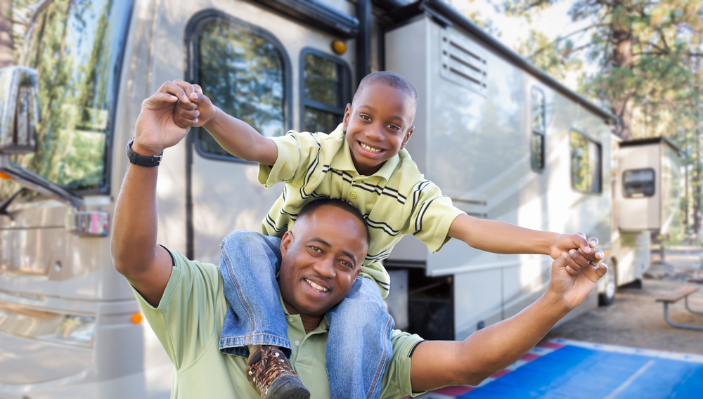 A Father and son smiling in front of a new RV purchased with a recreational loan from Telco